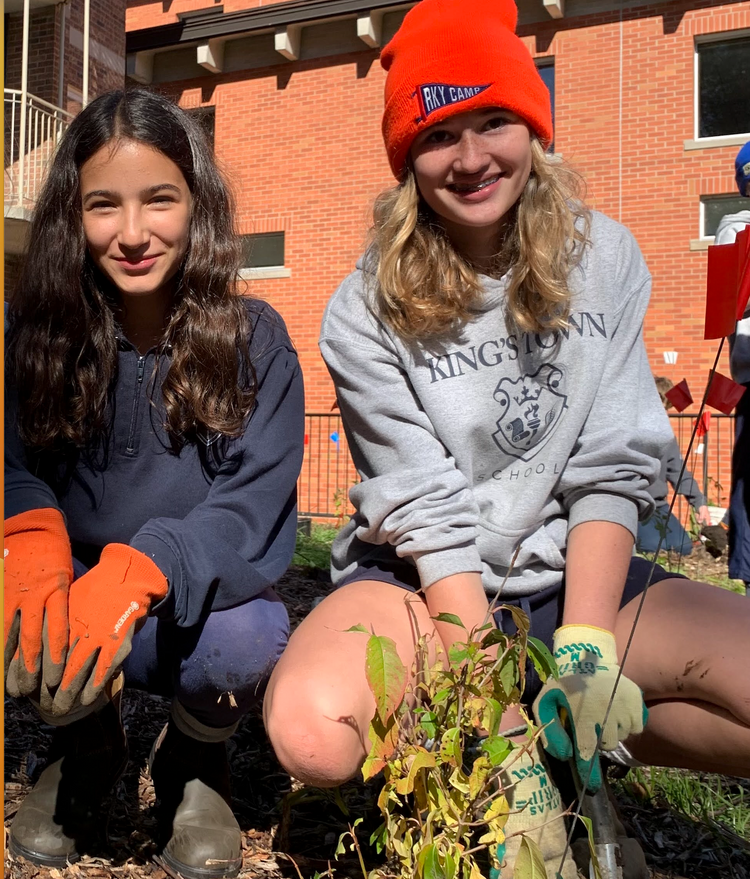 two smiling young people who just planted a tree